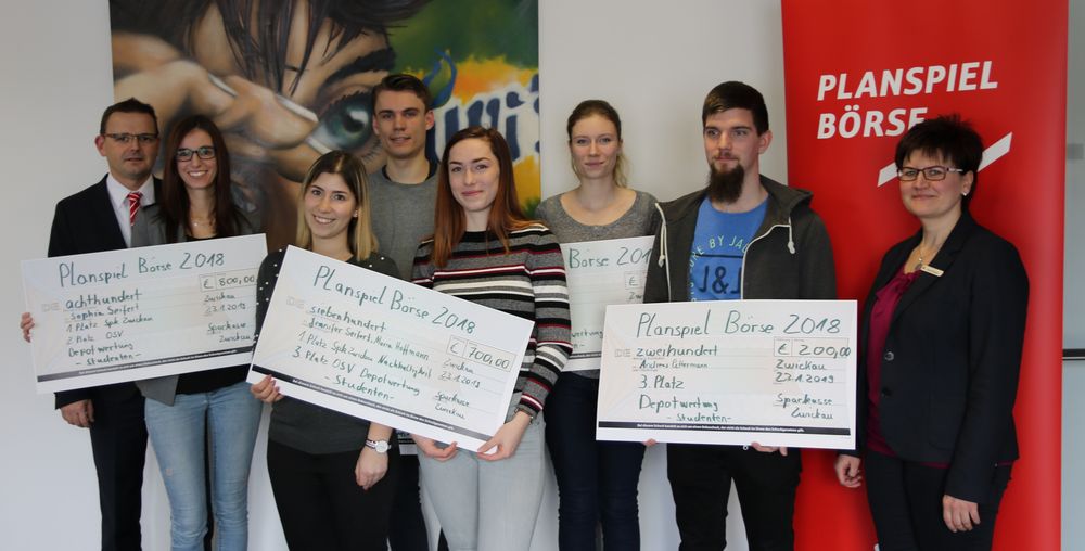 Gruppenfoto: Preisverleihung zum Planspiel Börse. Teilnehmer halten ihre großen symbolischen Schecks mit den Gewinnsummen in die Kamera.