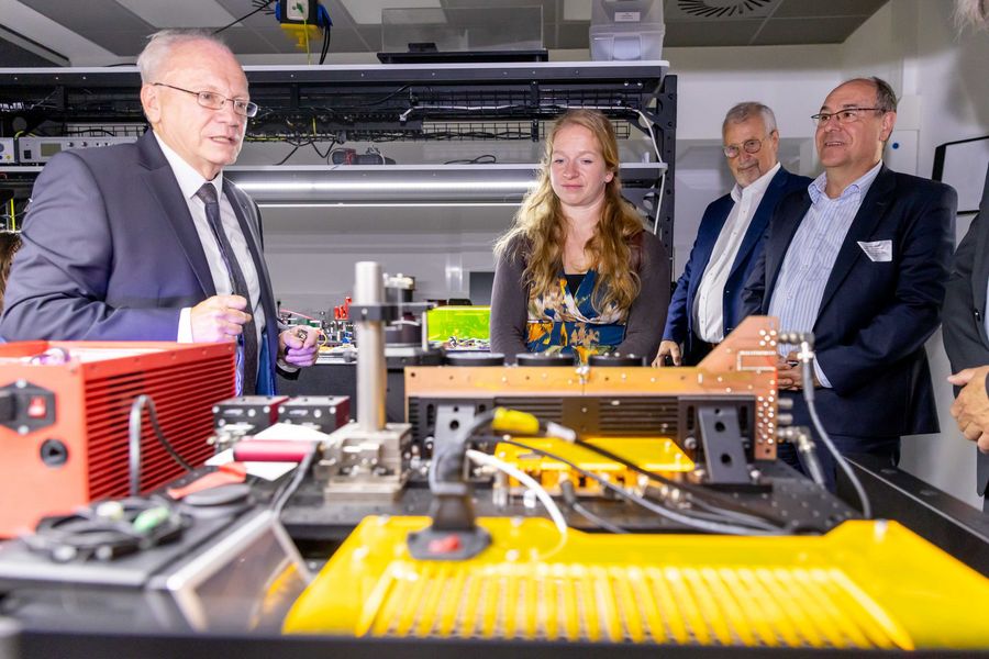Personen betrachten Versuchsaufbauten auf einem optischen Labortisch. 