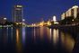 Foto: Blick bei Nacht über den Fluss mit beleuchteter Uferpromenade und Hochhaus in Tianjin.