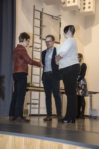 Foto: Zwei Absolventen erhalten eine Gratulation und ihre Urkunden.