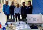 Gruppen von fünf jungen Menschen eng zusammenstehend an einem Stand auf einem Markt