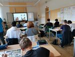 Aufnahme einer Schulklasse von hinten, auf der digitalen Tafel schreibt jemand ein chinesisches Zeichen.