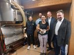 Eine Gruppe von Personen steht vor einer Ölpresse.