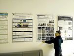 Foto: Eine Frau steht an einer Wand und richtet ein Poster an der Wand aus.