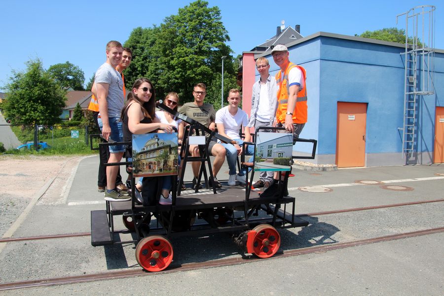 Foto: Studierende sitzen auf einem Draisinenwagen.