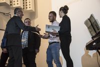 Foto: Vier Absolventen erhalten eine Gratulation und bekommen ihre Urkunden überreicht.