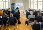 Personen präsentieren vor Zuhörern in einem Saal.