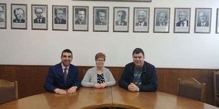 Foto: Frau Prof. Walter mit zwei weiteren Professoren sitzen an einem Konferenztisch und blicken lächelnd in die Kamera.