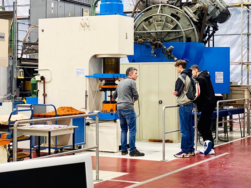 Labormitarbeiter erklärt Schülern an der Maschine