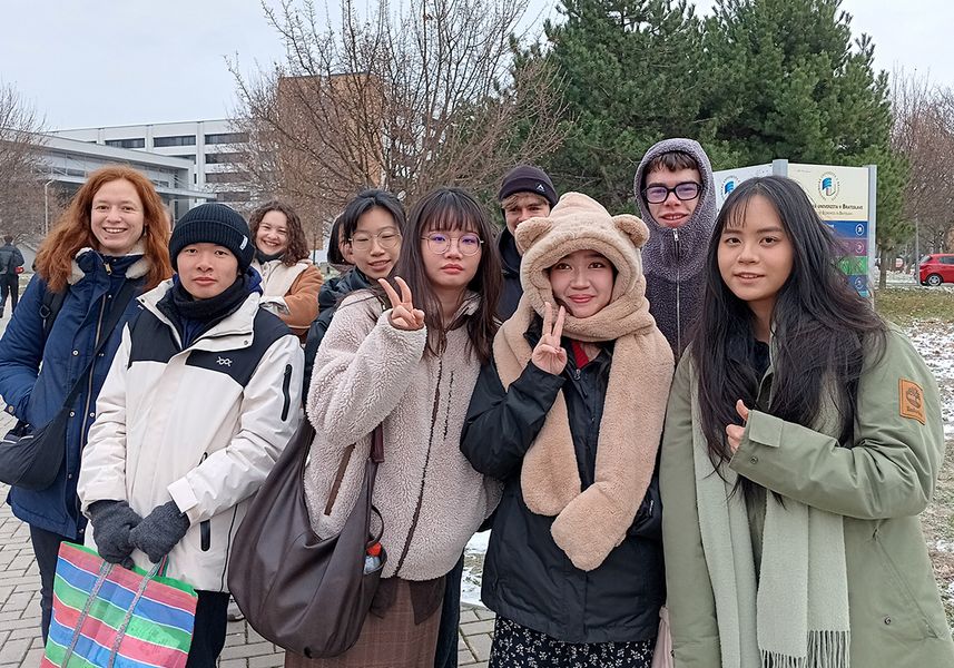 Gruppenfoto auf dem Uni-Campus. Die Teilnehmer winken in die Kamera. 