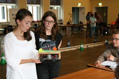 Foto: Zwei Schülerinnen präsentieren einer Jury ihr Modellauto.
