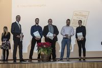 Gruppenfoto: Vier Absolventen präsentieren mit dem Gratulanten ihre Urkunden.
