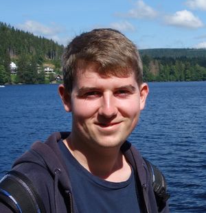 Foto: Person vor einem See schaut in die Kamera