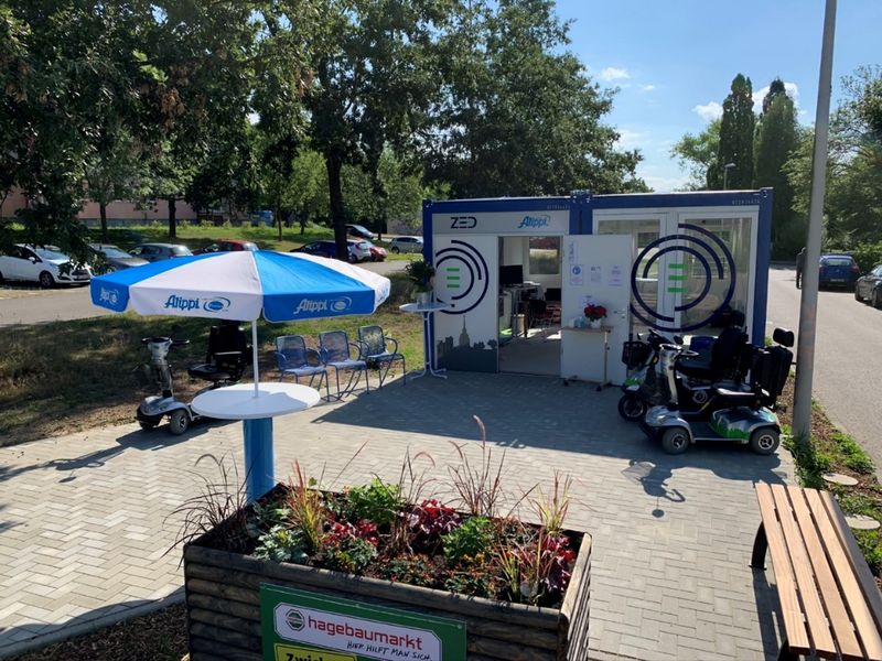 Eine bunt beklebte Garage, davor stehen E-Scooter zur Ausleihe. 
