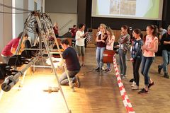 Foto: Schülerinnen stehen an der Lichtteststrecke und beobachten wie ein Mitarbeiter ihr Solar Modellauto auf die Teststrecke platziert.