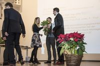 Foto: Zwei Absolventen bekommen Blumen überreicht.