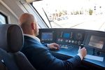 Foto: Ein Lokführer im Cockpit eines Zuges, Hand am Steuerhebel, Blick nach vorn.