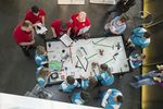 Schüler und Lehrer stehen um einen Legospieltisch