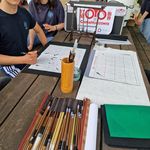 Auf einem Tisch liegen Kalligraphie-Stifte, Pinsel und Papier.