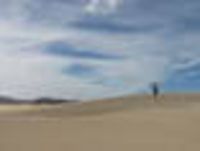 Foto: Eine Sanddüne mit einem Mädchen darauf.