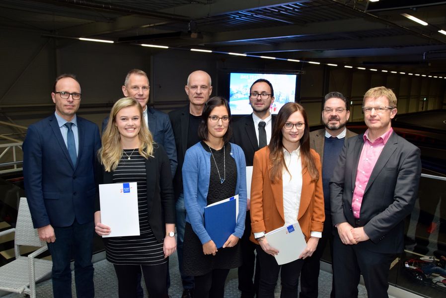 Foto: Neun Personen stehen auf dem Gruppenbild beieinander und schauen in die Kamera. 