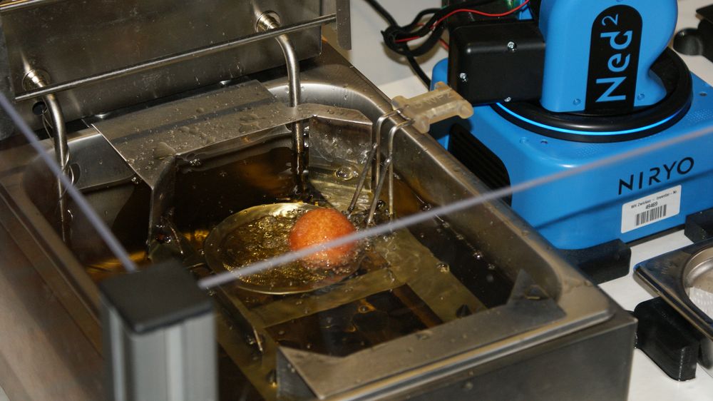 Roboter mit im Fett schwimmendem Krapfen im Vordergrund