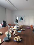 Foto: Auf zwei zusammengestellten Tischen stehen Gebäckteller, Tischlampen, Bücherstapel und kreative Spielsachen.