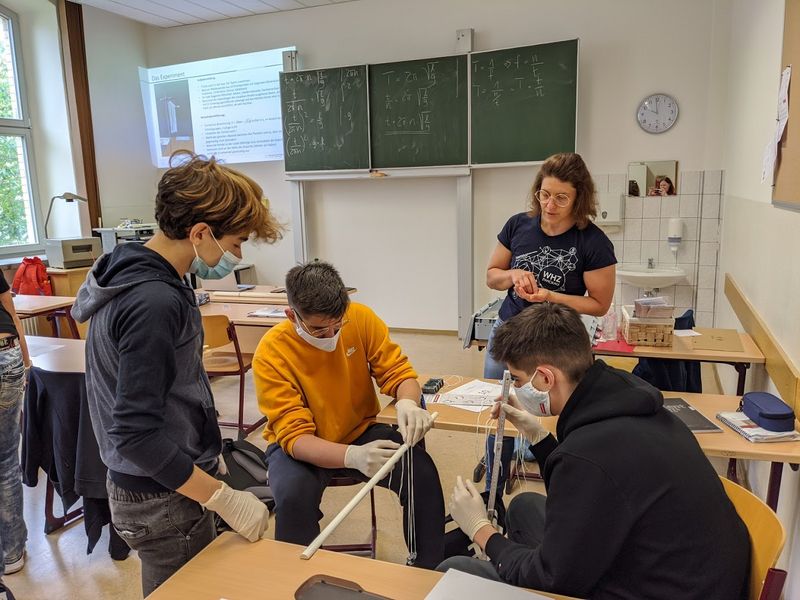 Foto: Gymnasiasten tätigen ein physikalisches Experiment in einem Klassenraum.