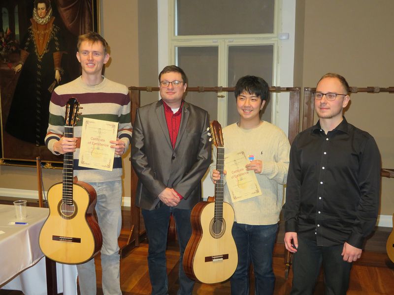 Gruppenbild mit vier Personen. Zwei Personen halten ihre Gitarren in die Höhe. 