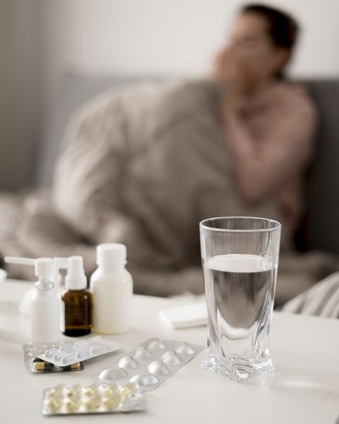 Glas Wasser, Tabletten, im Hintergrund eine verschwommene Person