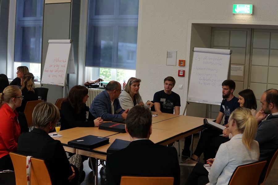 Foto: Studierende sitzen mit Unternehmensvertretern an Tischblöcken in der Aula Scheffelberg und tauschen sich aus.