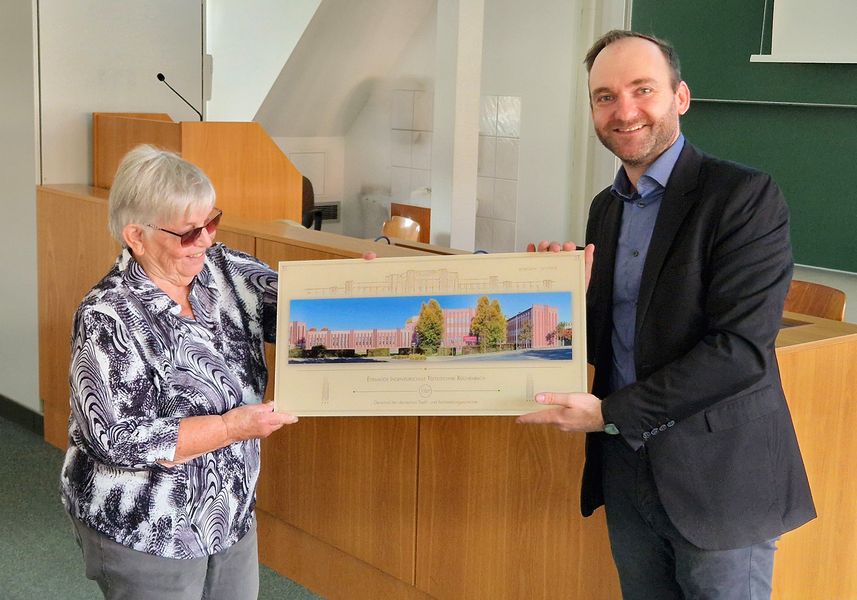 Zwei Personen präsentieren ein hochwertiges Foto und lächeln in die Kamera. 
