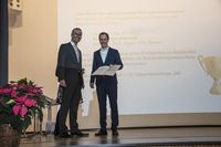 Foto: Ein Absolvent präsentiert seine Urkunde.