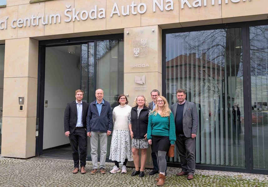 Ine Gruppe von Personen steht vor einem modernen Gebäude. 