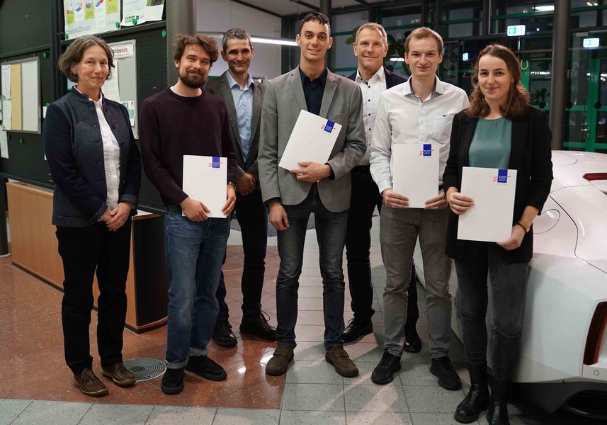 Gruppenbild mit Studierenden und Professoren. Personen lächeln und halten Urkunden in der Hand. 