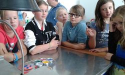 Foto: Sechs Mädchen stehen um einen Tisch und bekommen etwas vorgeführt.