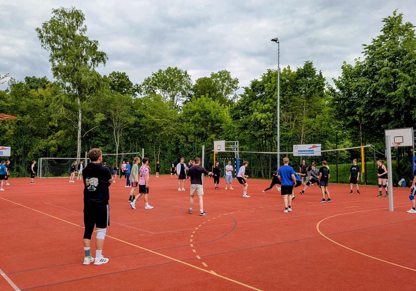 Menschen spielen Volleyball auf einem Tartanplatz.