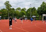 Menschen spielen Volleyball auf einem Tartanplatz.