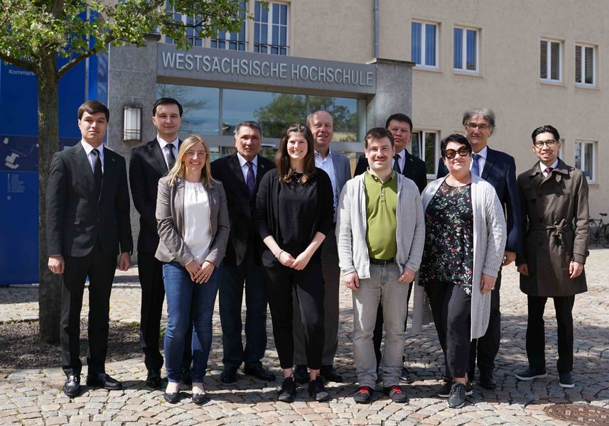 Eine Gruppe von Personen steht vor einem Eingang mit Schriftzug Westsächsische Hochschule Zwickau. 