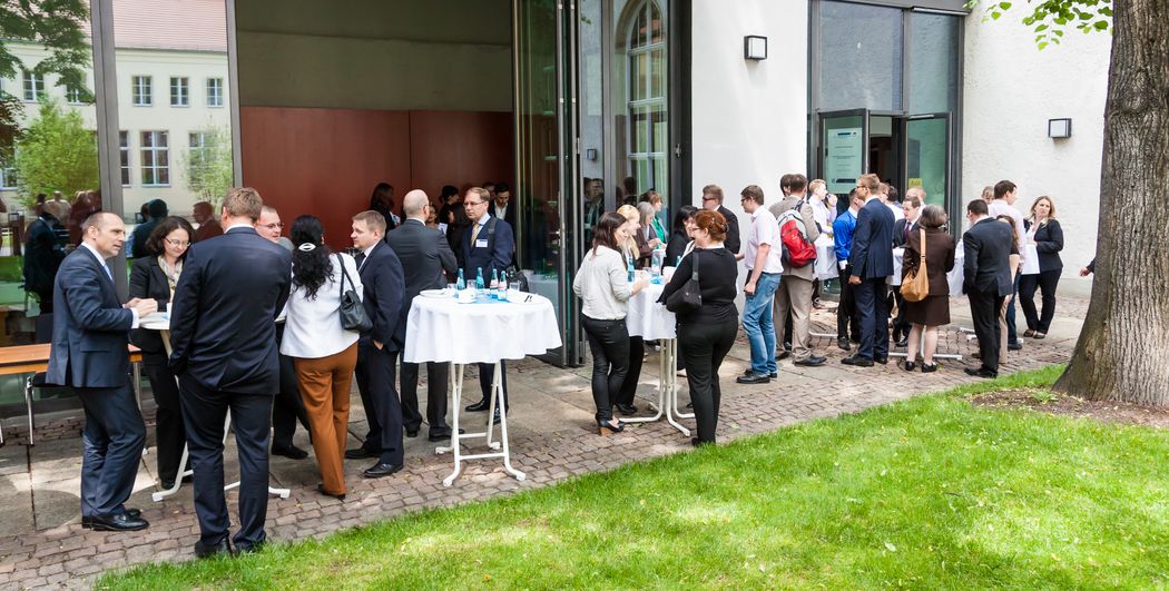 Foto: Teilnehmer stehen vor der Aula und unterhalten sich.