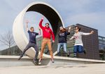 Studierende in Hochschulkleidung springen vor Looping