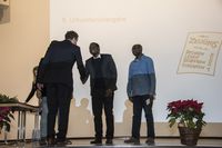 Foto: Drei Absolventen erhalten eine Gratulation und bekommen Urkunden überreicht.