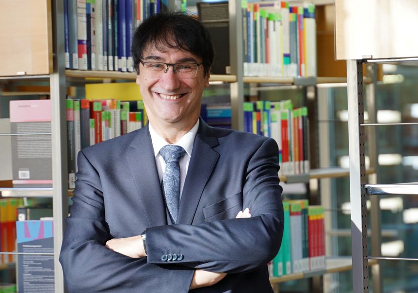 Portraitbild Prof. Stephan Kassel in Hochschulbibliothek, im Hintergrund Bücherregale