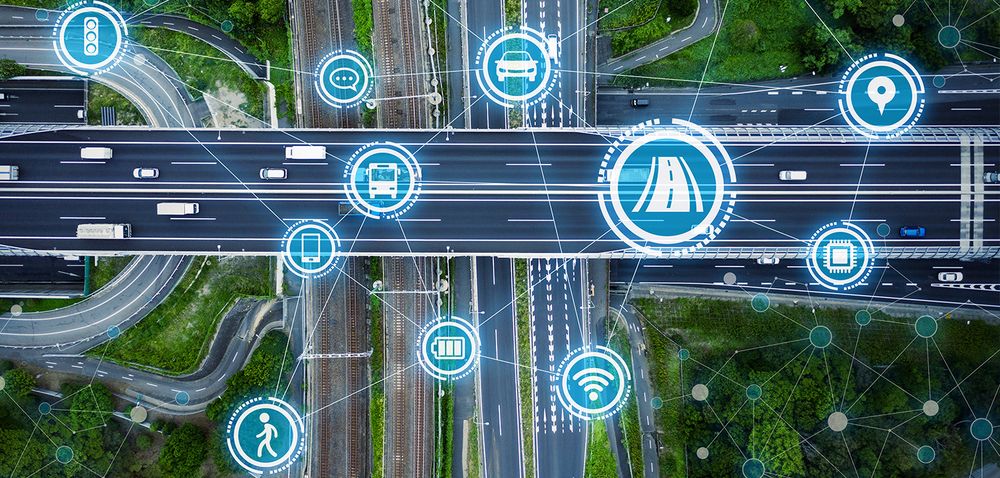 Mobilität_und_Verkehr (Illustration: metamorworks/adobestock) ; zu sehen ist eine Straßenkreuzung mit vielen Ebenen, Schienen und Fahrzeugen. Darüber gelegt ist ein Netz aus transparenten Kreisen mit Symbolen von Fahrzeugen, Akkus, und Kommunikationsgeräten.