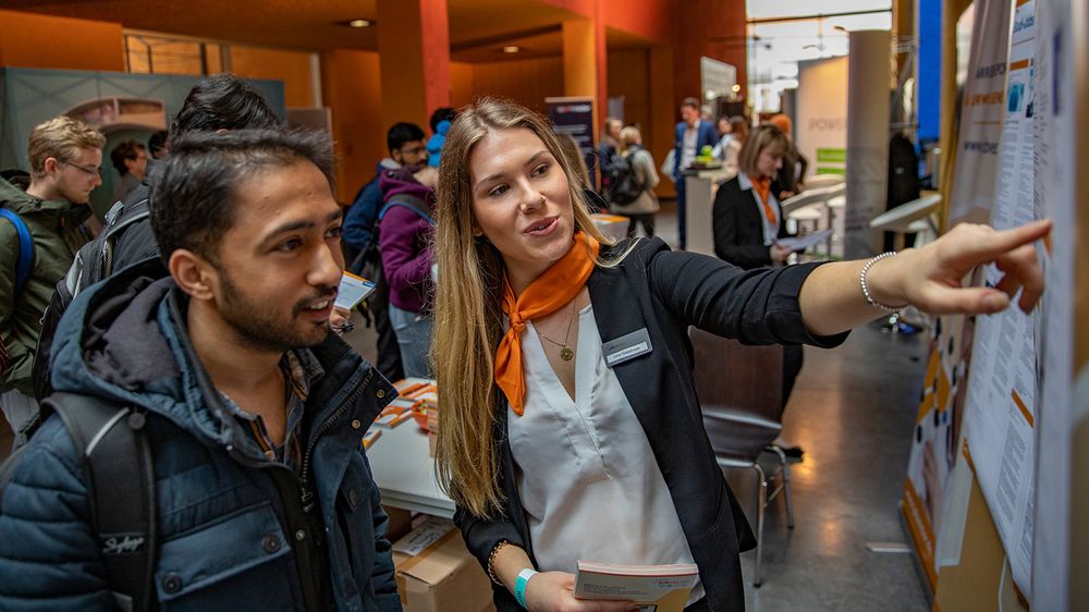 Eine Beraterin und ein Studierender unterhalten sich auf einer Jobmesse. 