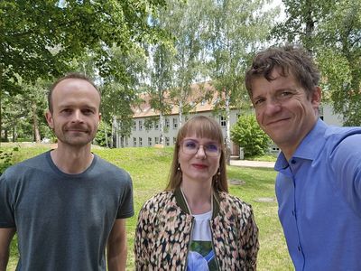 Die drei Vorstandsmitglieder des IEV sind draußen fotografiert mit viel grün und dem Lehrgebäude im Hintergrund | Quelle:WHZ