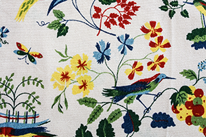 Foto: Ausschnitt einer Stickarbeit mit Vögeln, Schmetterlingen und Blumen.