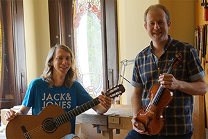 Foto: Zwei Herren im Bild. Einer mit Gitarre und der andere mit einer Geige in der Hand.