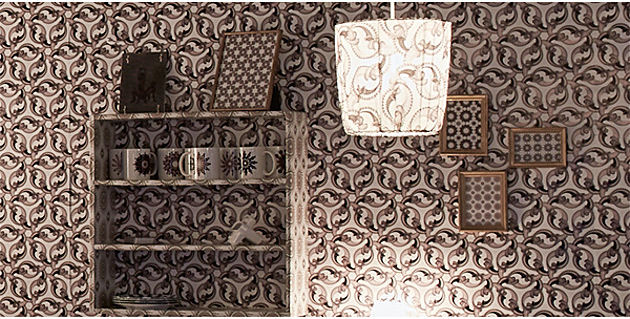 Foto 3: Ein Bücherregal, Lampenschirm und Bilder an der Wand in einem Raum. Zusammenarbeit mit Schweizer Projektgruppe Delgadofuchs.