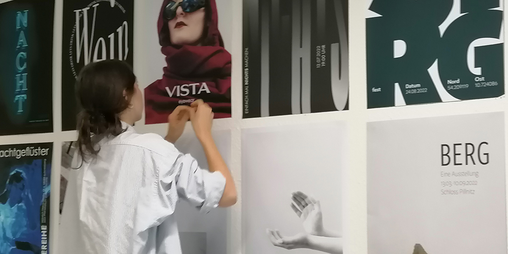 Foto: Studierende steht vor Wandplakaten